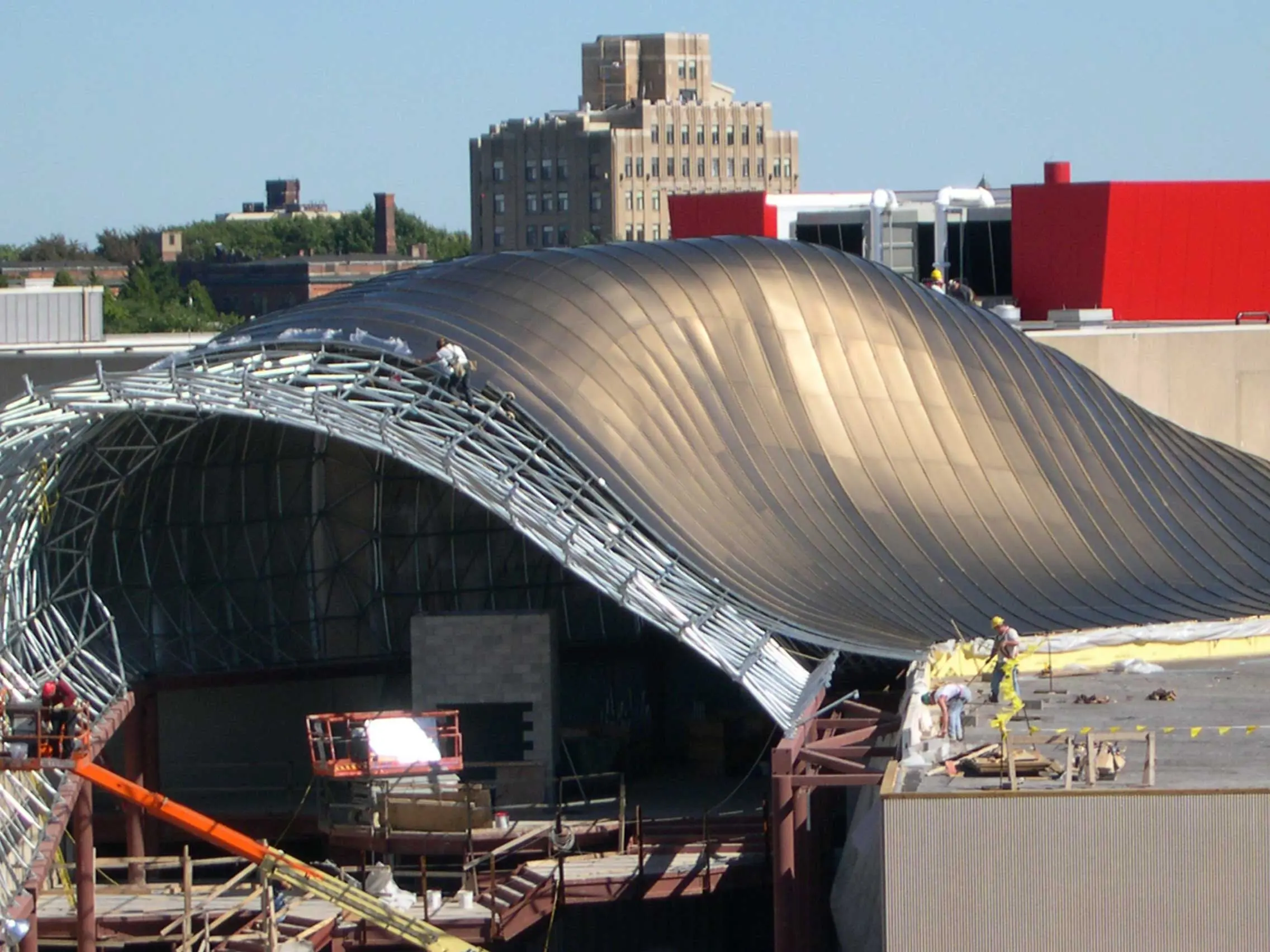 Techo de estructura space frame de forma libre en proceso de instalación con paneles de revestimiento metálico, mostrando geometría curva compleja e integración estructural en un proyecto moderno.