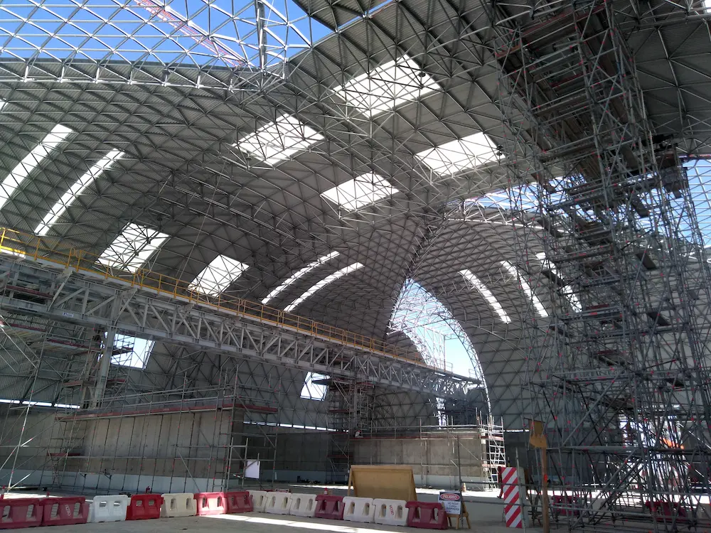 Vista interior del domo industrial Triodetic en construccion en la Mina Spence, mostrando la estructura de armazon espacial de acero, el andamiaje y los sistemas de soporte estructural.