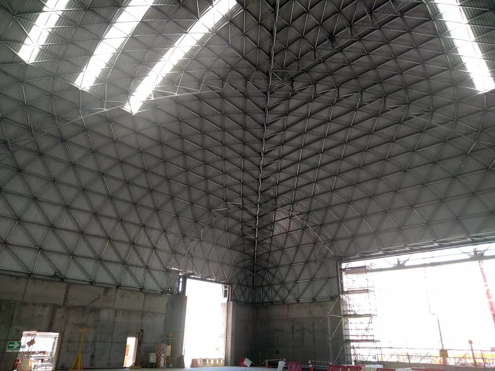 Interior del domo industrial Triodetic en la Mina Spence, con la estructura de marco espacial de acero, el revestimiento metalico corrugado y las grandes aberturas estructurales.