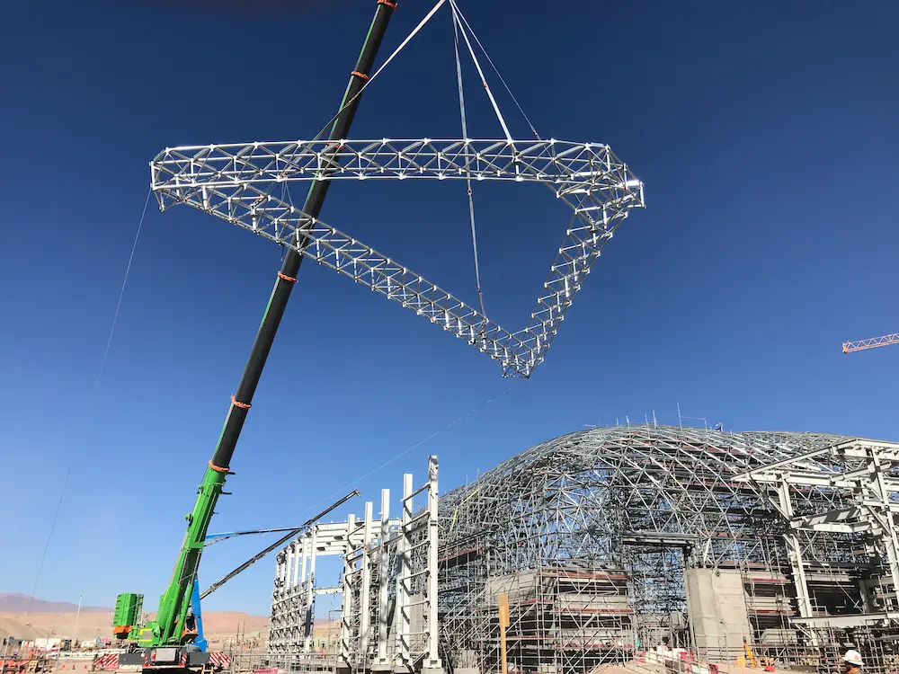 Seccion de marco espacial de acero Triodetic elevandose con una grua en la Mina Spence, mostrando la construccion del domo industrial y componentes estructurales de acero.